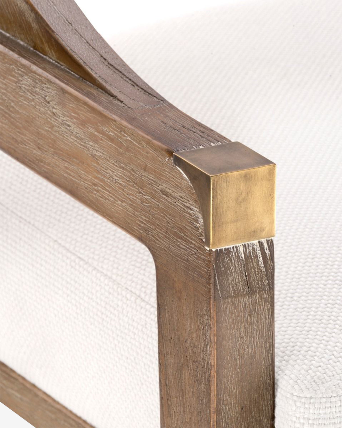 Close-up of the Jensen Counter Stool’s wooden armrest with a brass accent. The stool showcases textured white upholstery, a natural wood finish, and a hand-woven cane back made from solid Cape Lilac Mahogany, by Vendixs