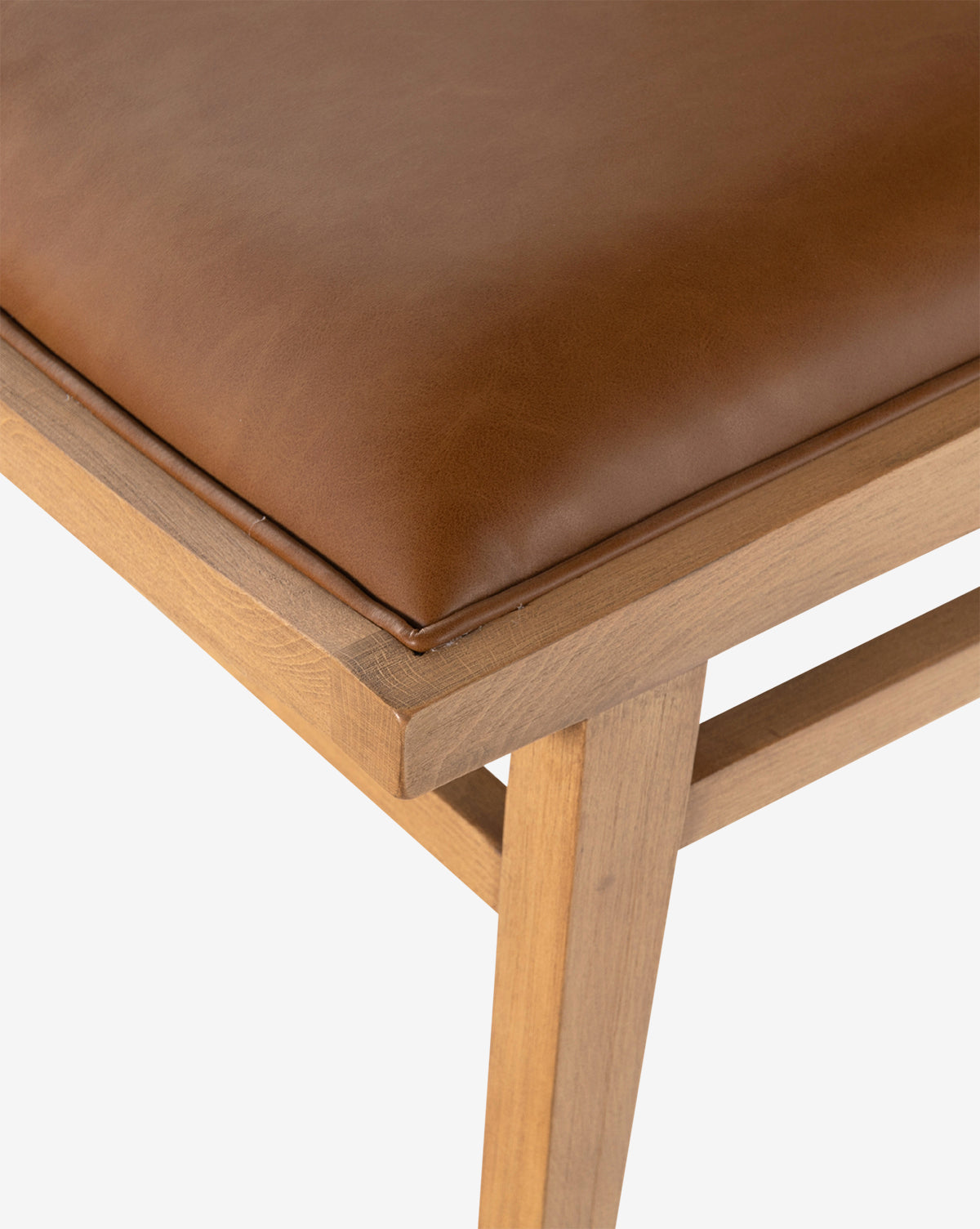 Close-up of the Jett Dining Chair, showcasing its sturdy beech wood frame and padded seat upholstered in smooth brown leather or faux leather, by Vendixs