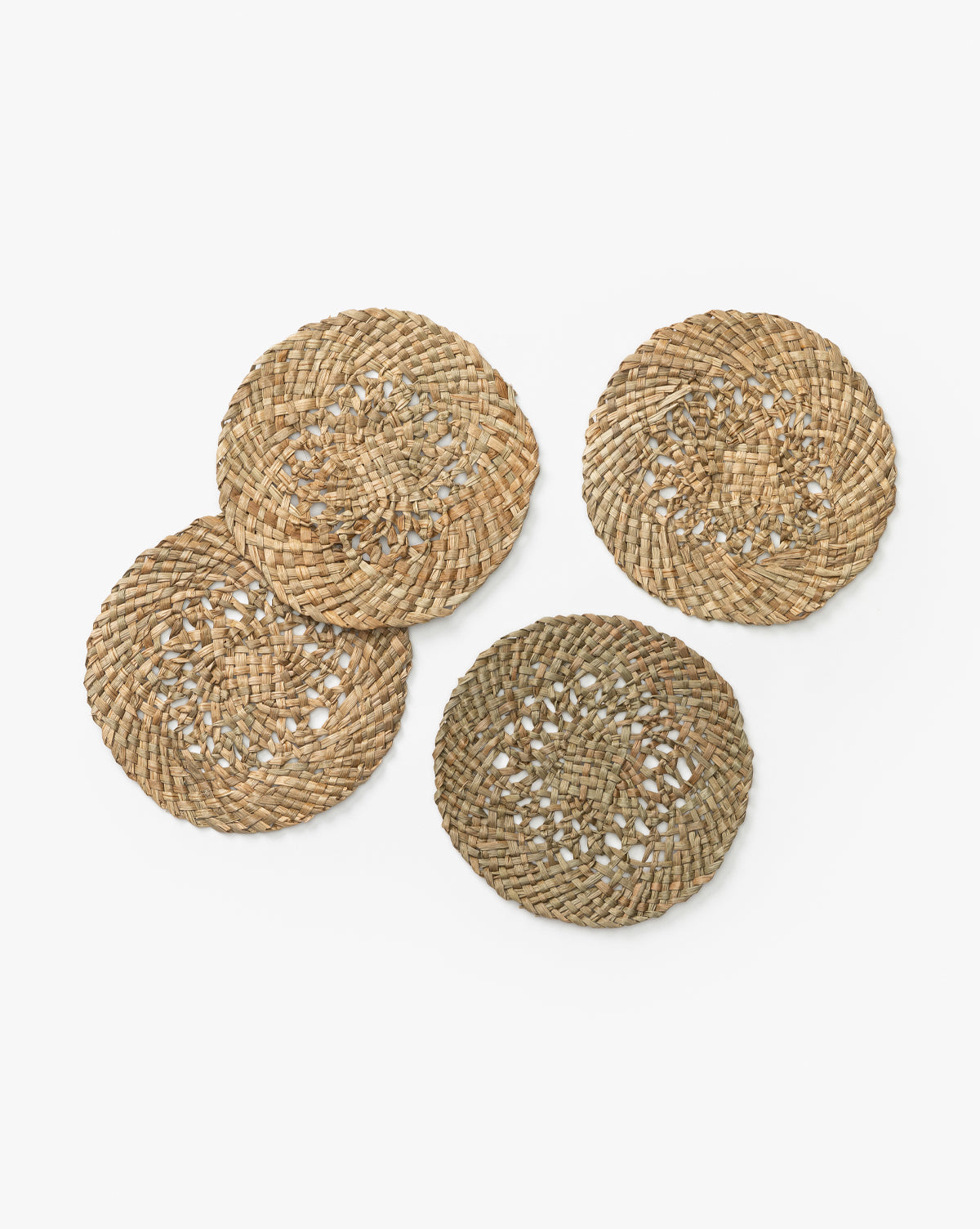 The Joanie Woven Coasters (Set of 4) are round and crafted from mendong grass. Each features unique shades and textures, bringing handmade charm to your table decor. Perfect for adding an organic touch to any setting, by Vendixs