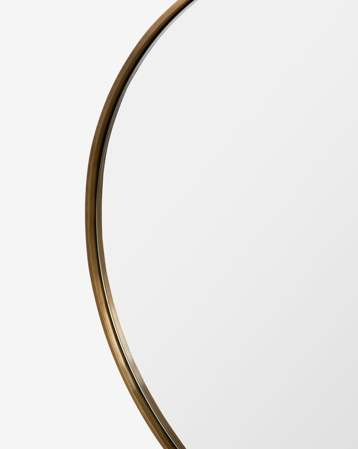 A close-up of the Laila Circle Mirror featuring a thin, metallic brass frame shown against a plain white background, by Vendixs