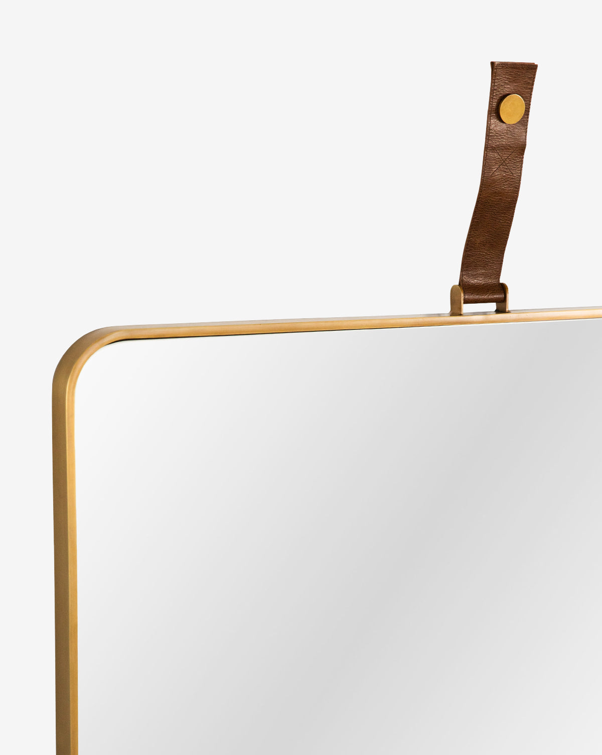 Close-up of the top corner of the Laila Rectangle Mirror, featuring a gold metal frame and brown leather hanger with brass hardware, set against a plain white background, by Vendixs