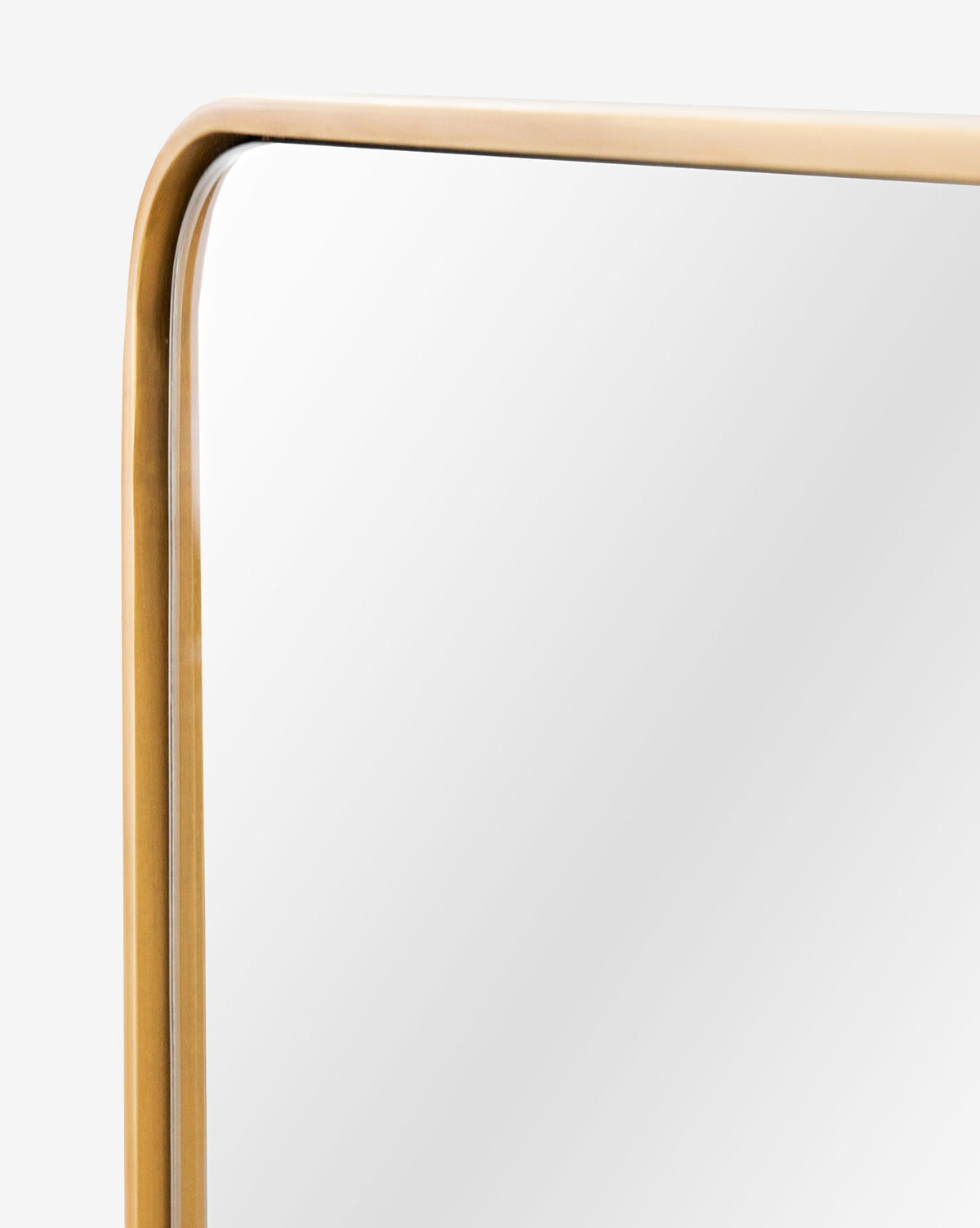 A close-up of the Laila Rectangle Mirrors top corner shows its rounded edge and gold metal frame with elegant brass hardware, set against a plain light background, by Vendixs