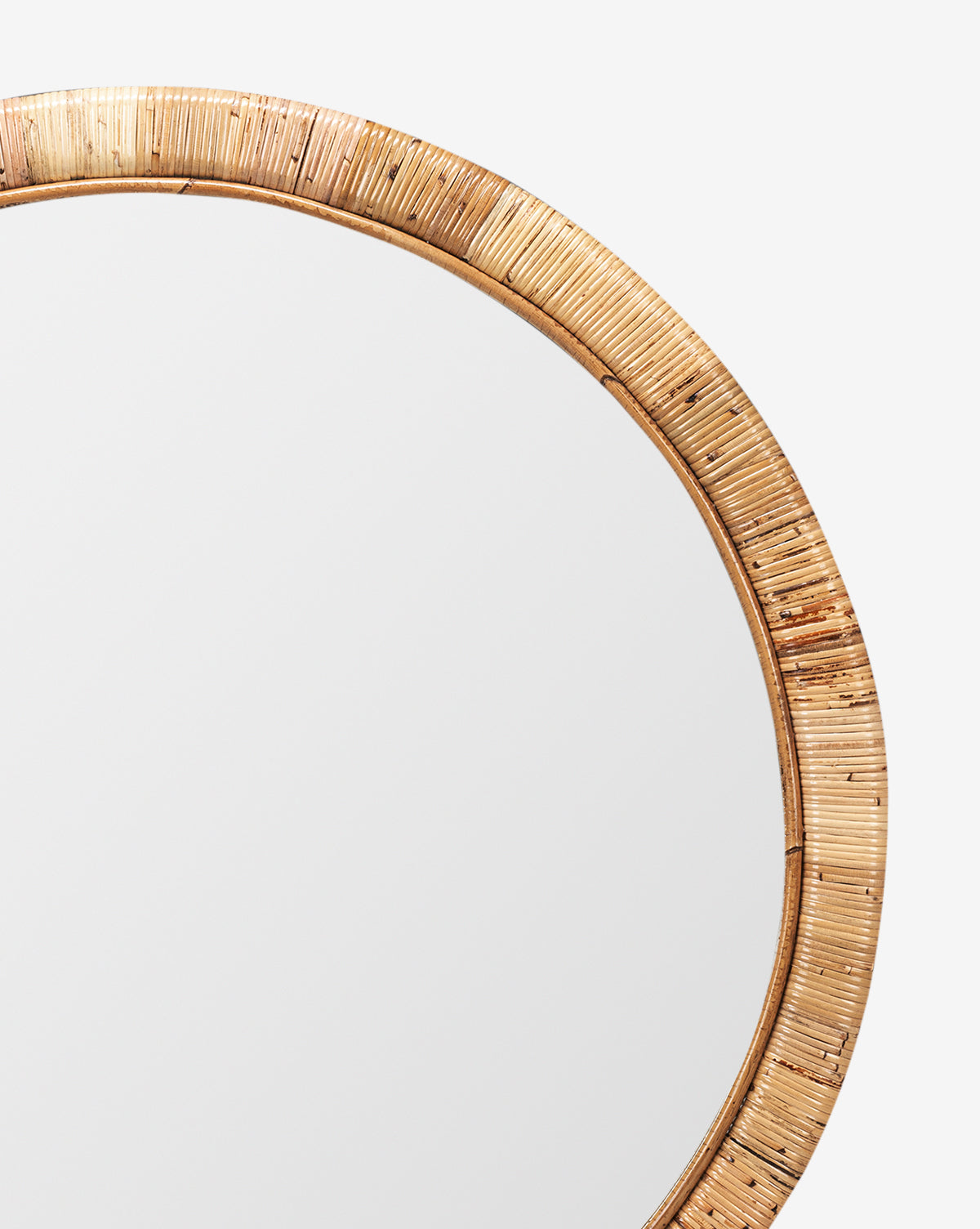A close-up of the Lenore Wall Mirror featuring a round shape and woven rattan frame, shown against a white background. The visible upper right section highlights its natural elements and transitional design appeal, by Vendixs