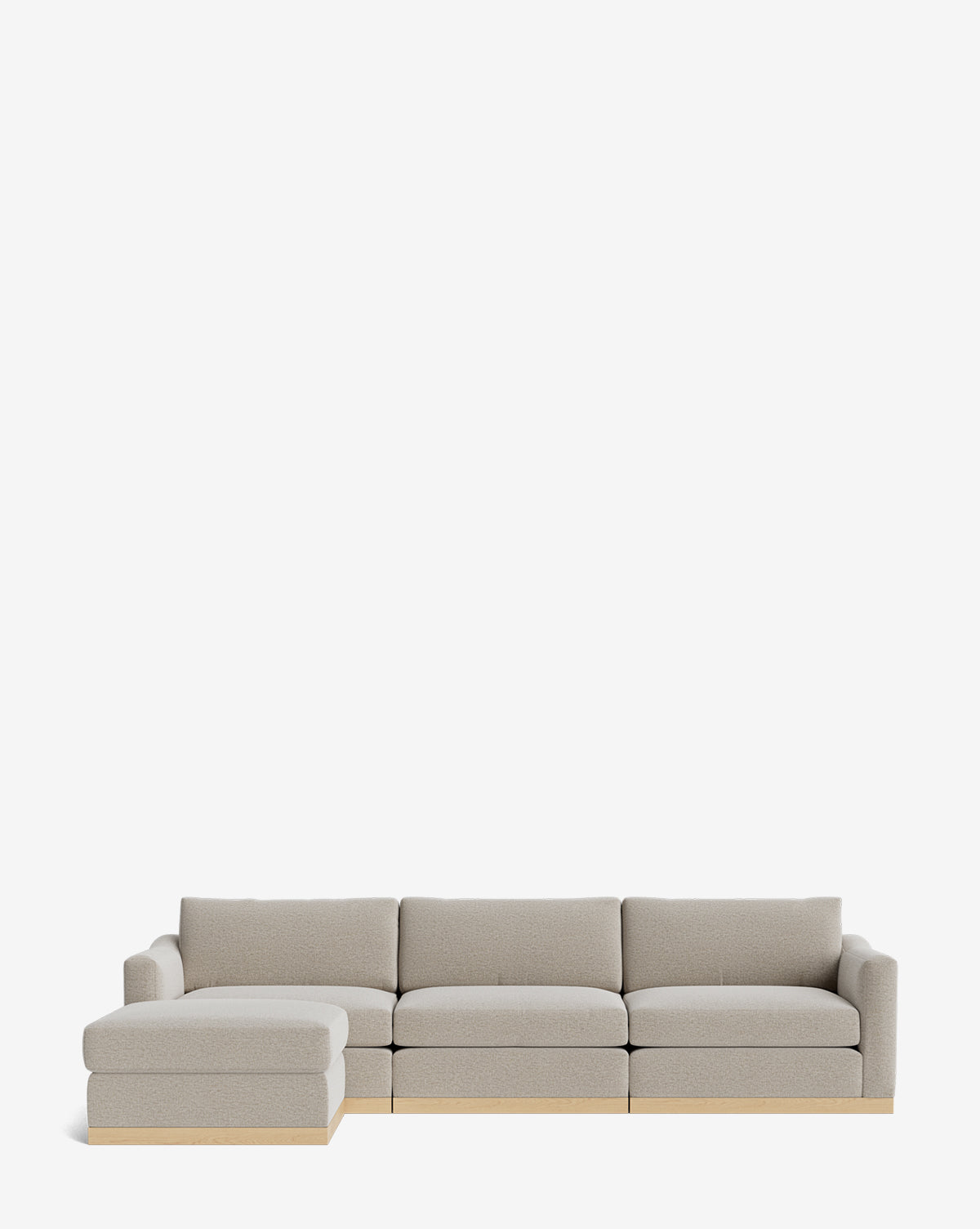 The Community Vernon Modular Sofa with Ottoman 121 is a light gray L-shaped sectional featuring customizable upholstery, a left chaise, three seat cushions, wooden base accents, and an ottoman, shown against a plain white background. Vendixs