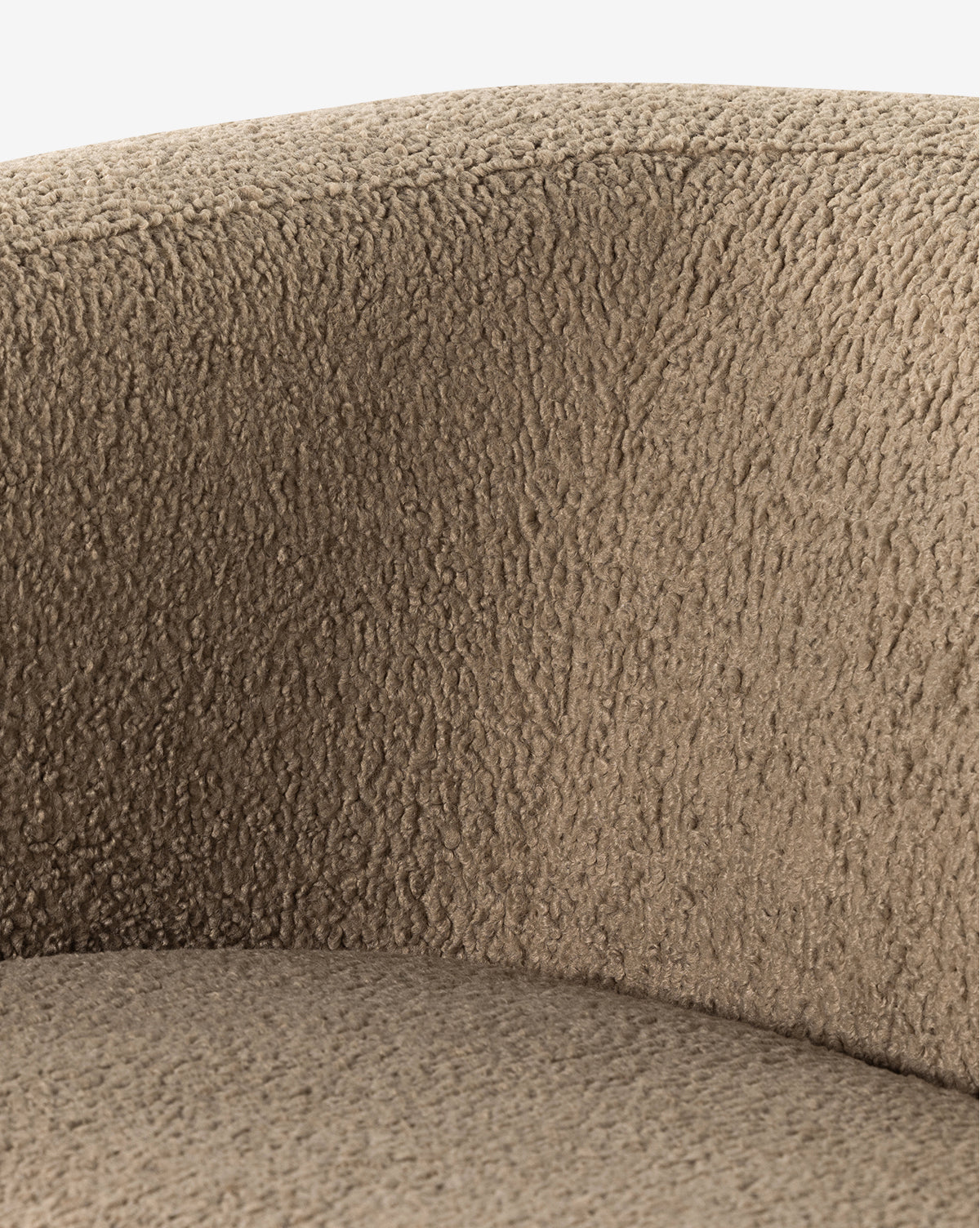 Close-up of the Quill Sofa 84 by Four Hands reveals its textured light brown, woolly upholstery and gently curved backrest, evoking the soft contours of a vintage sofa. Vendixs