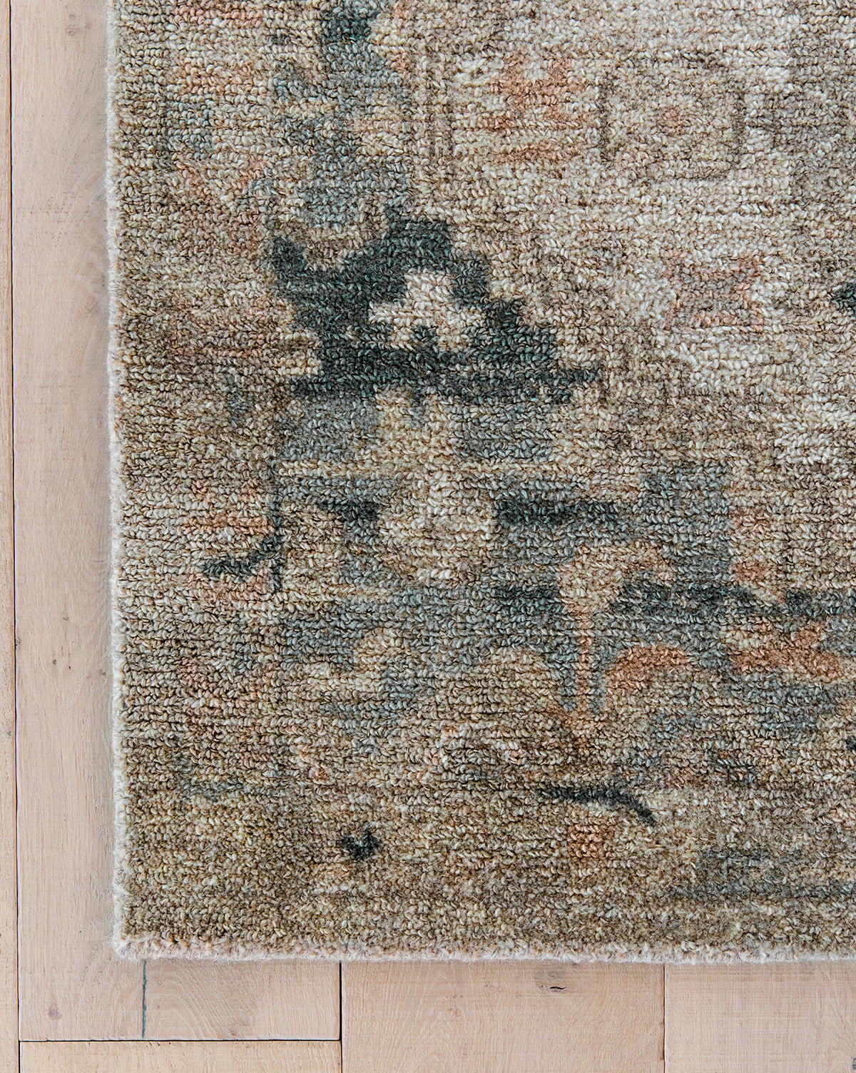 The Wilshire Blue Hand-Tufted Wool Rug displays muted beige, blue, and gray tones in a slightly distressed vintage design, offering timeless appeal, by Vendixs Shown here on a light wood floor.