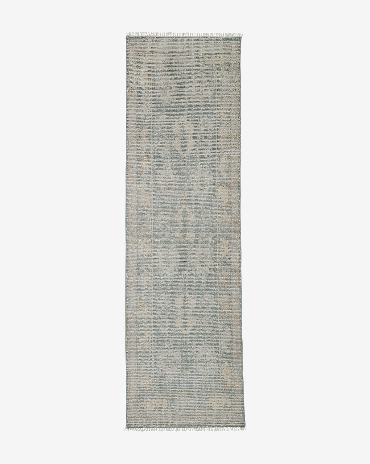 The Roslin Hand-Knotted Wool Rug is rectangular with a faded vintage-style pattern in muted blue and beige, featuring subtle geometric and floral motifs plus short fringe on the shorter ends, by Vendixs