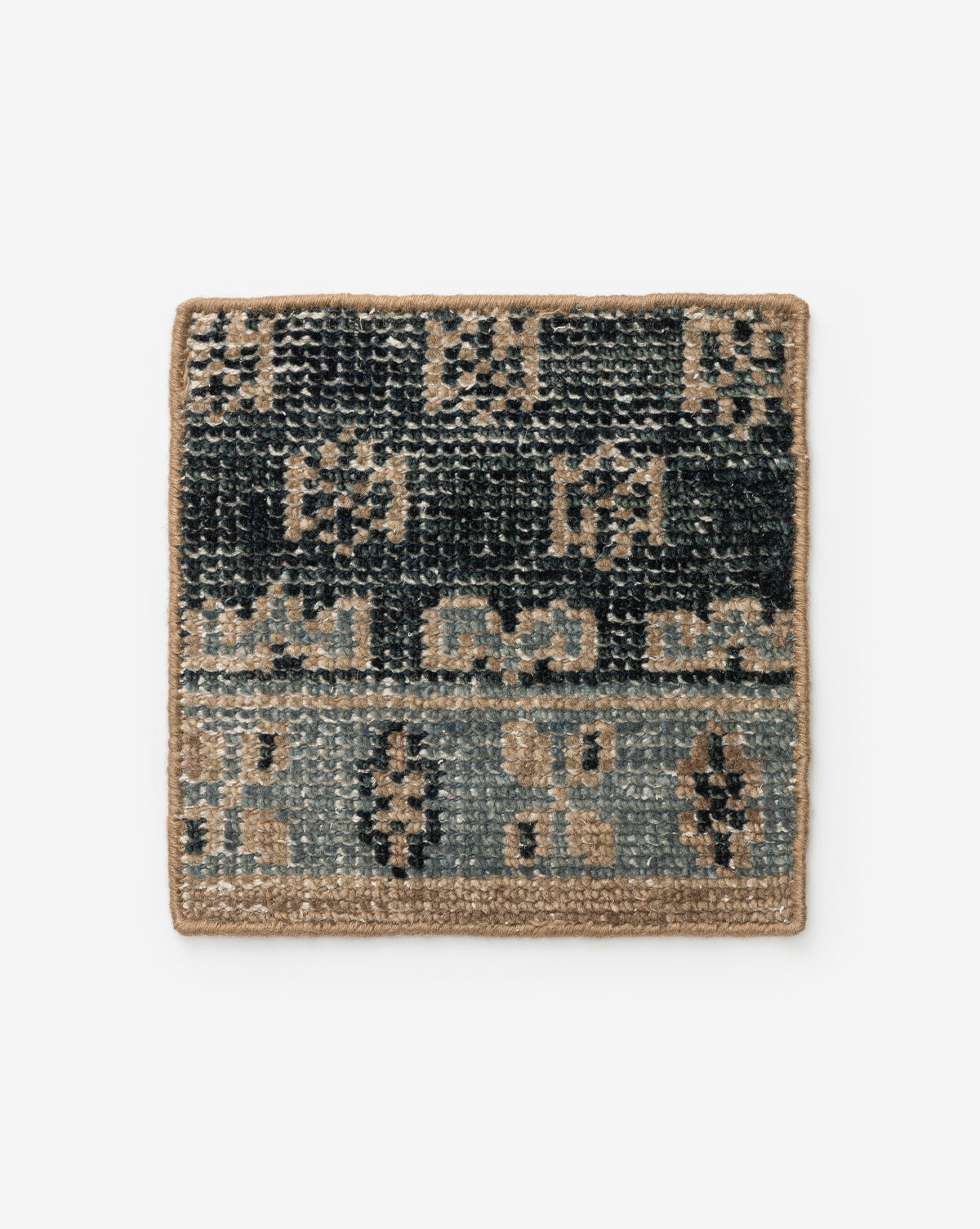 The Anya Indigo Hand-Knotted Rug Swatch by Obeetee features a square woven design with geometric patterns in black, gray, and tan tones with a tan border, inspired by transitional rugs, shown on a white background by Vendixs