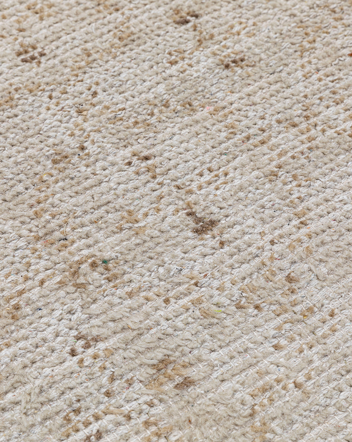A close-up of the Mali Hand-Knotted Rug in beige, showing visible brown stains and an uneven texture, by McGee & Co.