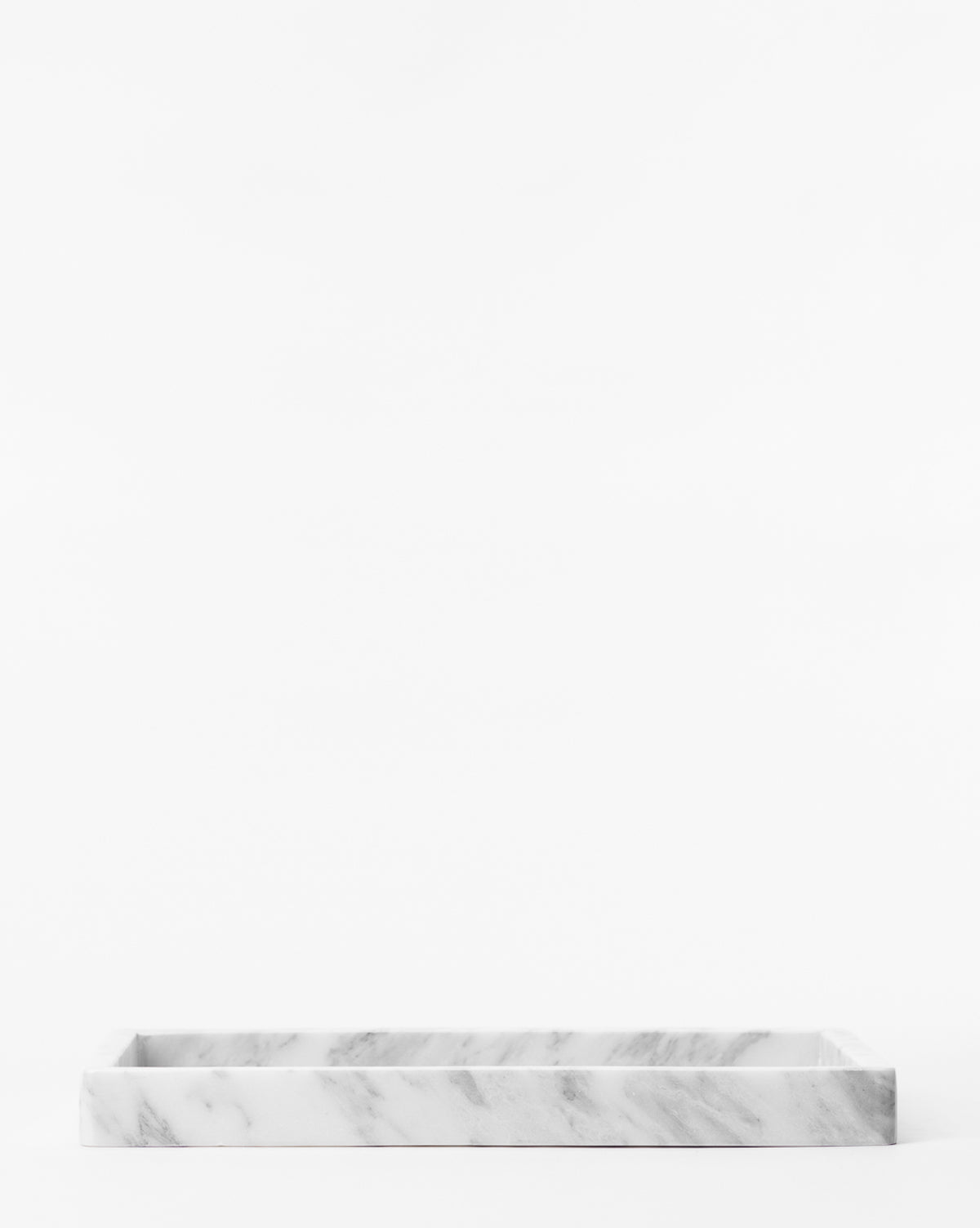 The Marble Tray, featuring subtle gray veining, rests on a white surface—ideal for use as a countertop tray to create minimal decorative displays against a clean white background.
