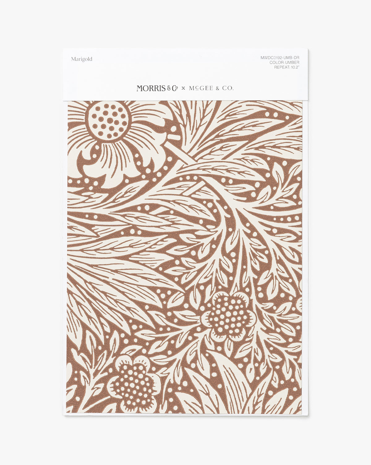 The Morris & Co. x Vendixs Marigold Umber Wallpaper Swatch features a brown and white marigold floral pattern with intricate leaves, packaged with a white label branded “McGee & Co.” Vendixs