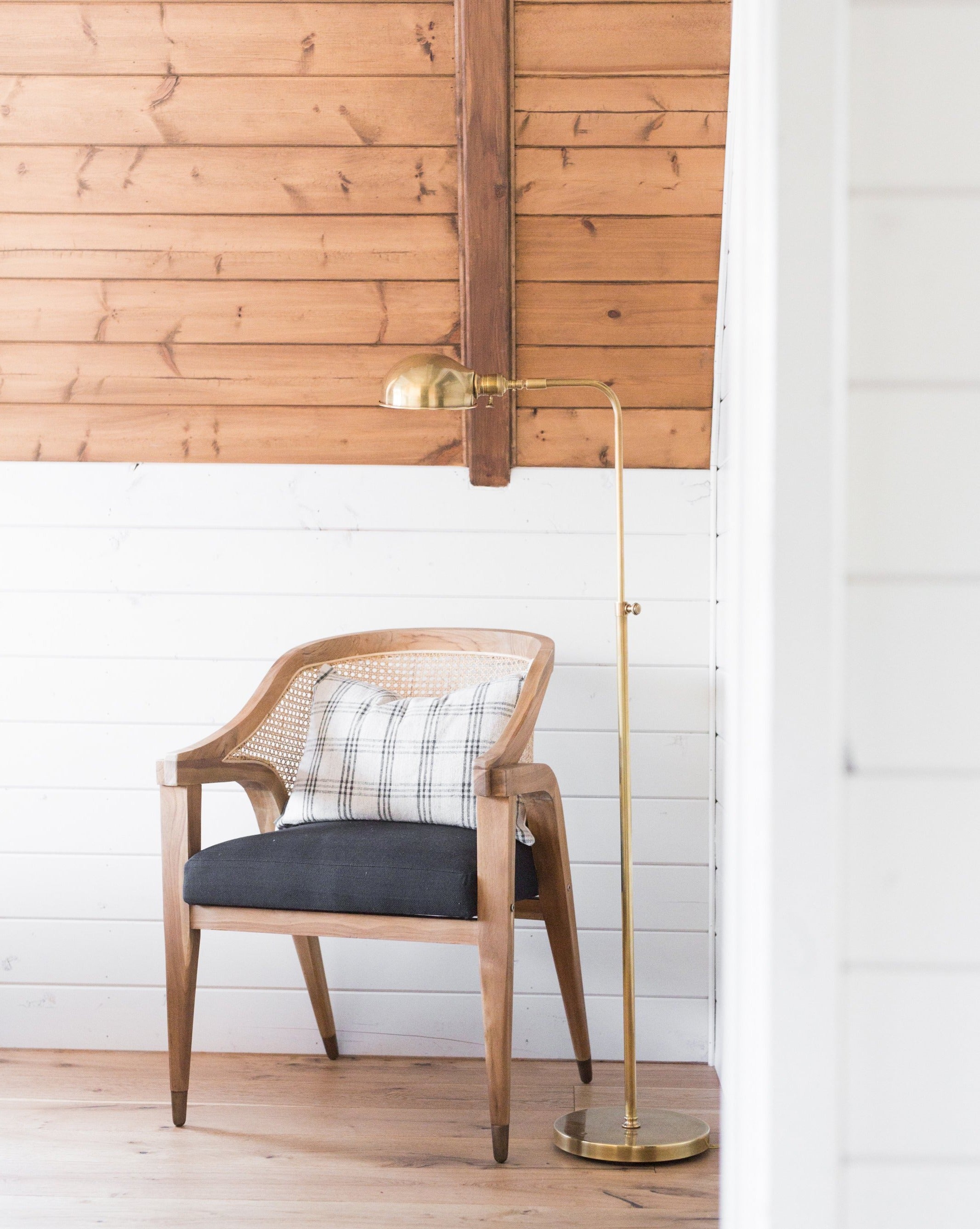 An Old Pharmacy Floor Lamp stands next to a wooden chair with a plaid cushion and dark seat in a cozy corner featuring white shiplap walls and a sloped wooden ceiling, by Vendixs
