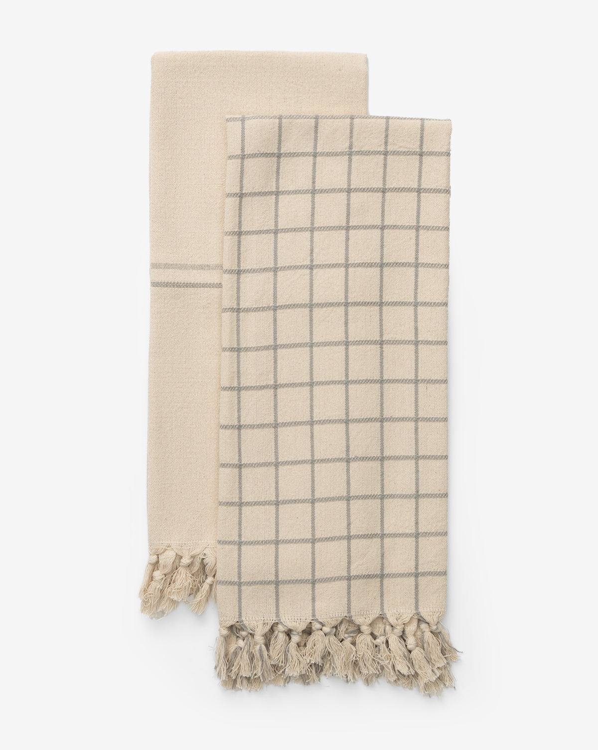 The Peabody Cotton Tea Towel Set includes two beige towels—one striped, one with a gray grid—each finished with tasseled fringes, adding charming style to your kitchen decor, by Vendixs