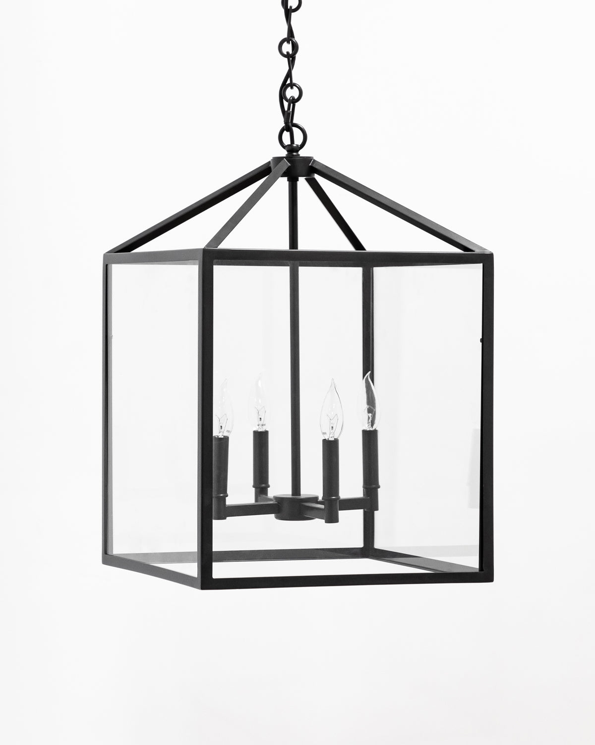 The Makerspalm Pietro Lantern Pendant is a black metal geometric chandelier with clear glass panels, featuring four candle-style bulbs in a rectangular frame, suspended by a chain. Vendixs