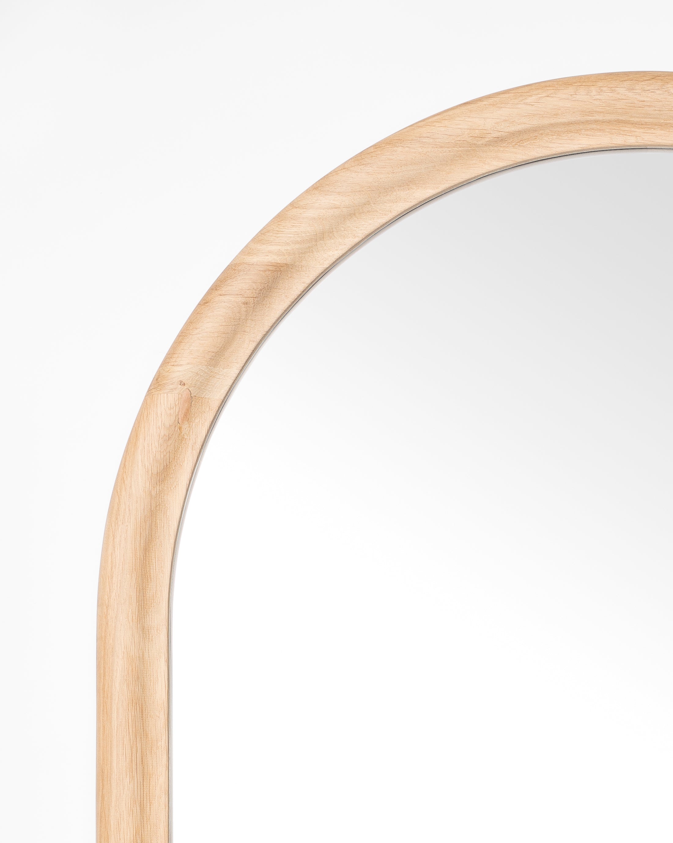 A close-up of the upper left corner of the Reta Arched Wall Mirror, showcasing its light natural oak frame and arched design, set against a plain white background, by Vendixs