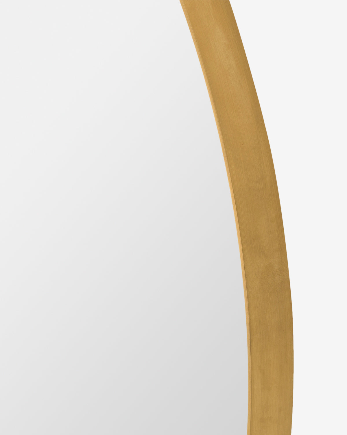 Close-up of the Solange Mirror, featuring a minimalist design with a gold-colored, rounded frame and partial brass finish against a white background. Only part of the mirror’s reflective surface and elegant edge are visible by Vendixs