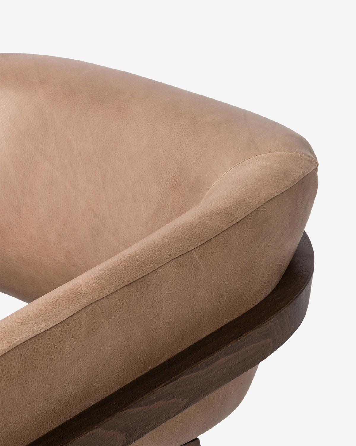 Close-up of the Stanley Lounge Chair, upholstered in light brown leather with curved padding and a dark wooden frame, set against a plain white background for a contemporary look, by Vendixs