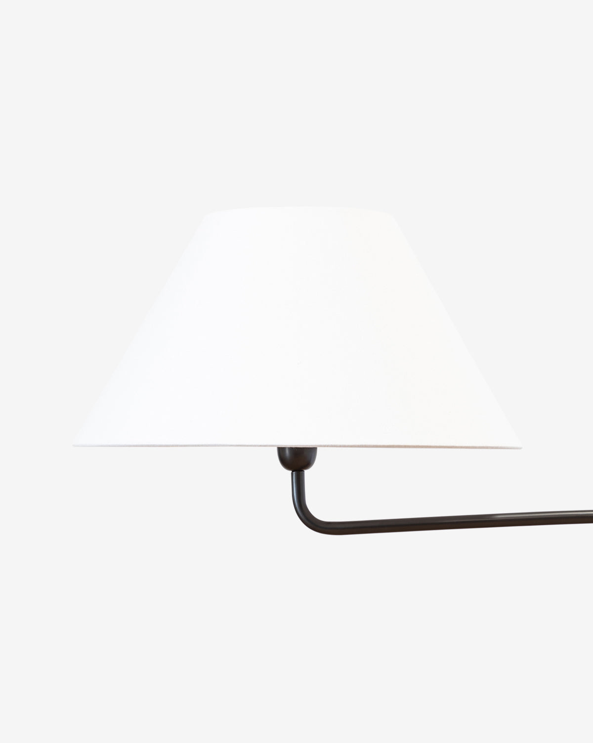 The Wainwright Swoop Floor Lamp features a minimal design with a white conical lampshade and a sleek black metal arm that extends horizontally, channeling vintage elegance against a plain, light background, by Vendixs
