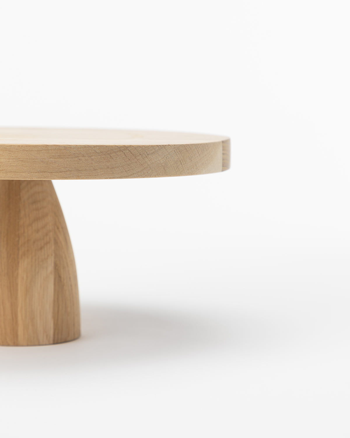 The Wooden Cake Stand features a minimalist design with a round top and sturdy base, shown partially against a plain white background, by Vendixs