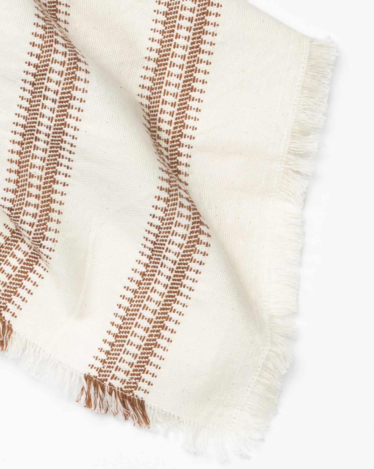 The Woven Stripe Tea Towel is a cream cotton kitchen towel featuring brown geometric stripes and fringed edges, shown on a white background, by Vendixs