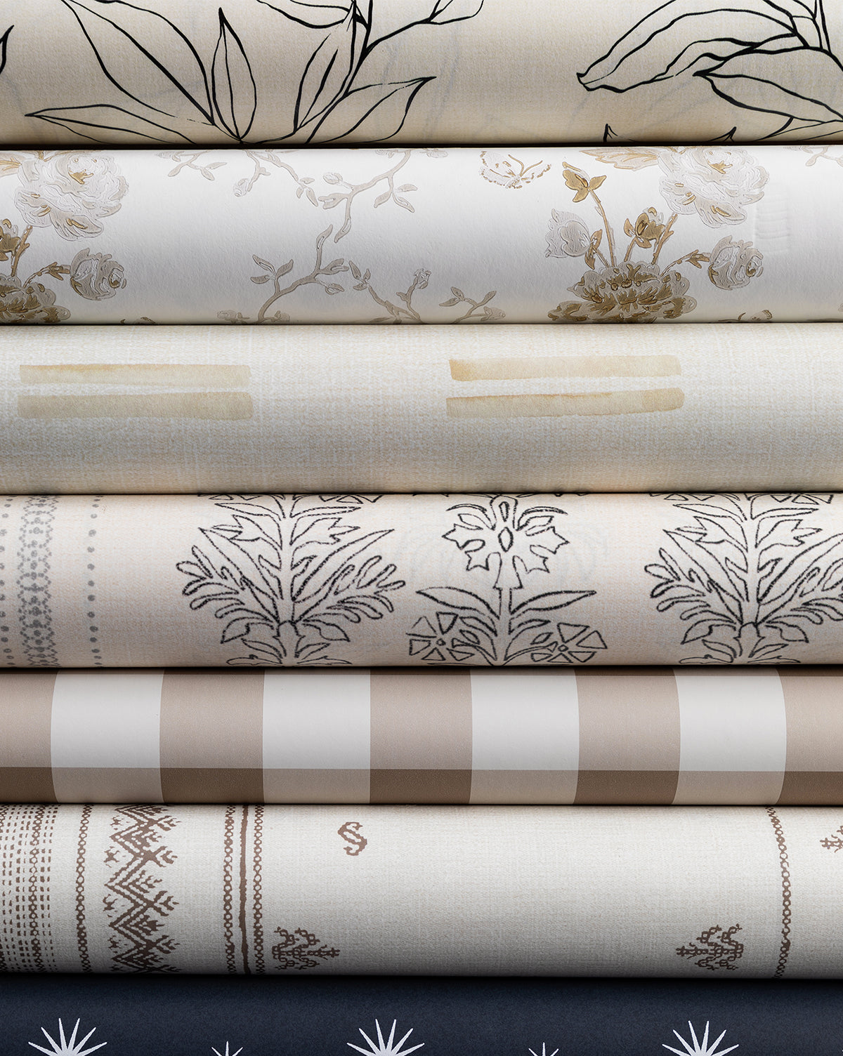 A selection of folded neutral fabrics, each with a unique pattern—florals inspired by Cecile Floral Print Wallpaper by York Wallcoverings, botanicals, stripes, checks, and geometrics—displayed against a plain background by Vendixs